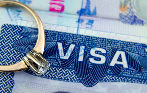 A close-up photo of a Visa document and a wedding ring.